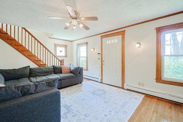 living area featuring stairway, a ceiling fan, wood-type flooring, and a baseboard heating unit