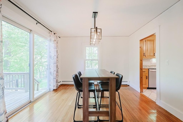 dining room featuring baseboards, a baseboard heating unit, and light wood-style flooring