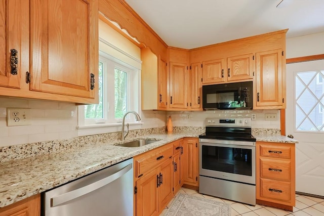 kitchen with stainless steel appliances, light stone counters, a healthy amount of sunlight, and a sink