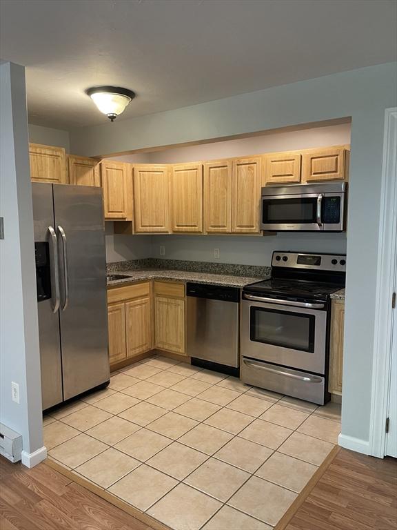 kitchen featuring stainless steel appliances, light brown cabinetry, and light tile patterned floors