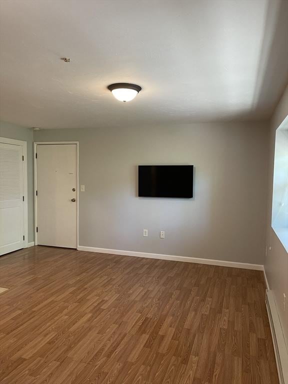 empty room featuring dark wood-type flooring and a baseboard radiator