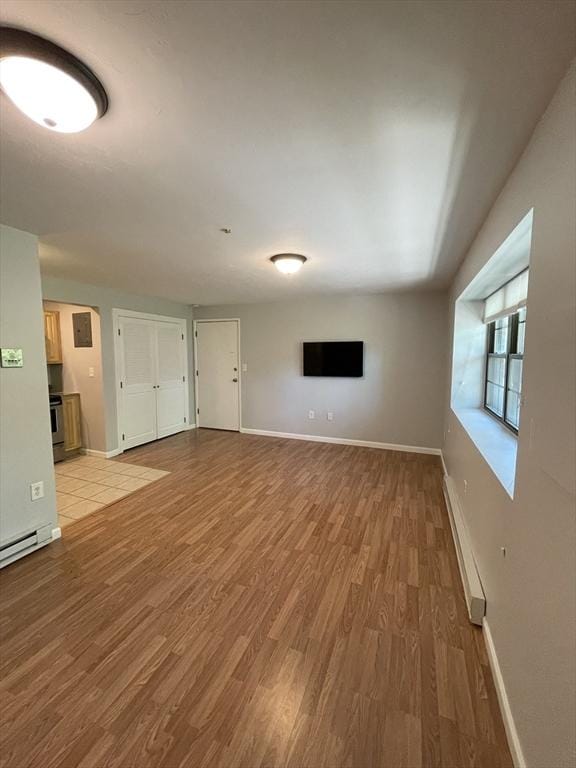 unfurnished living room featuring light hardwood / wood-style floors and a baseboard heating unit