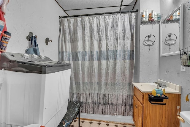 bathroom featuring vanity, toilet, and a drop ceiling