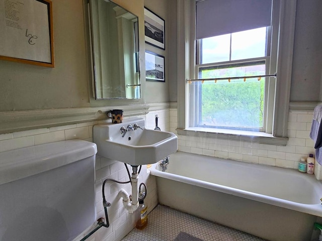 5 Crawford St Unit 9, Cambridge, MA 02139 - bathroom featuring tile walls, a bath, a wainscoted wall, and tile patterned floors