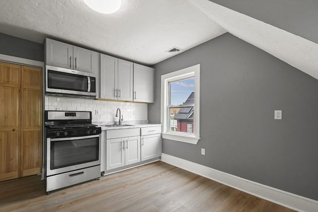 69 Greenwood St, Boston, MA 02122 - kitchen featuring appliances with stainless steel finishes, light wood finished floors, backsplash, light countertops, and baseboards