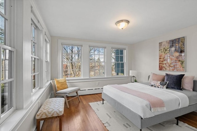 bedroom with a baseboard heating unit and wood-type flooring