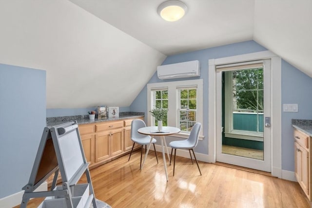 dining area with light wood-style flooring, a wall mounted AC, baseboards, and vaulted ceiling