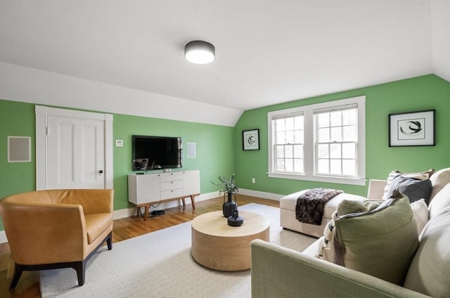 living area featuring baseboards, lofted ceiling, and wood finished floors