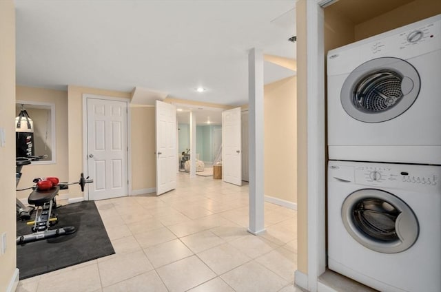 washroom with light tile patterned floors, laundry area, stacked washer and clothes dryer, and baseboards