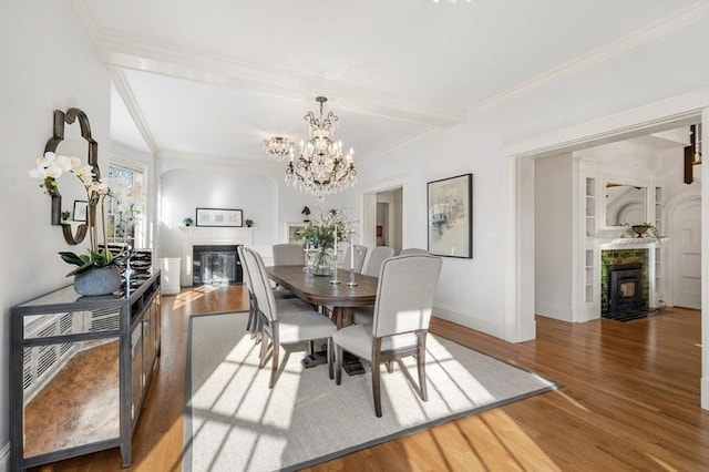 dining room with a chandelier, a fireplace with flush hearth, baseboards, and wood finished floors