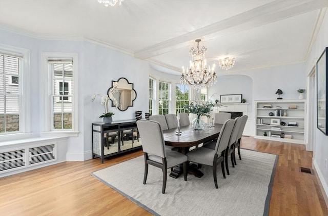 dining area with visible vents, ornamental molding, an inviting chandelier, and wood finished floors