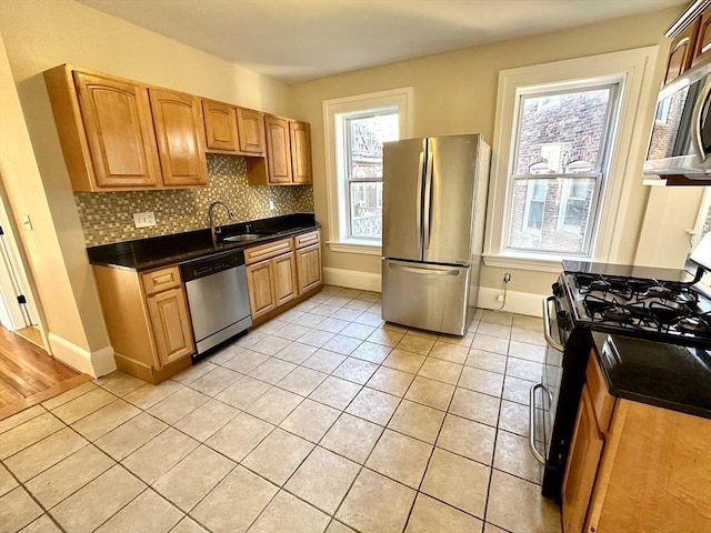 kitchen with tasteful backsplash, appliances with stainless steel finishes, light tile patterned flooring, and sink