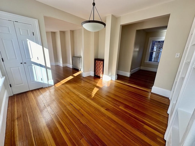 unfurnished living room with dark wood-type flooring and radiator heating unit