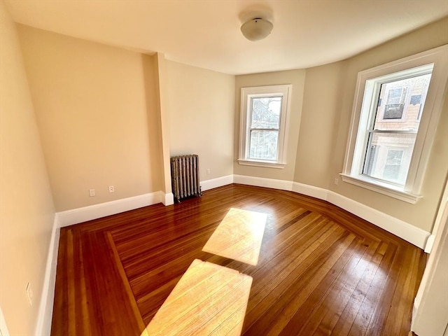 spare room featuring radiator and dark wood-type flooring