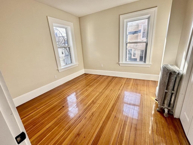 spare room with radiator heating unit and light wood-type flooring