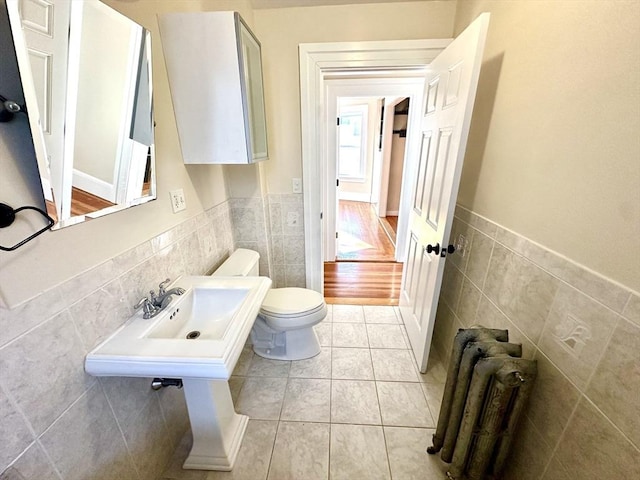 bathroom featuring tile patterned flooring, radiator, tile walls, and toilet