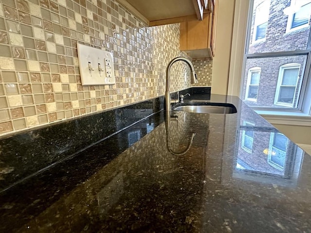 kitchen featuring tasteful backsplash, sink, and dark stone counters