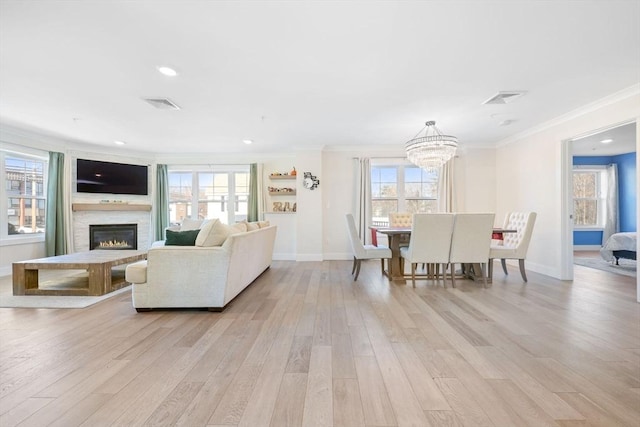 living room with crown molding, a wealth of natural light, and light hardwood / wood-style floors