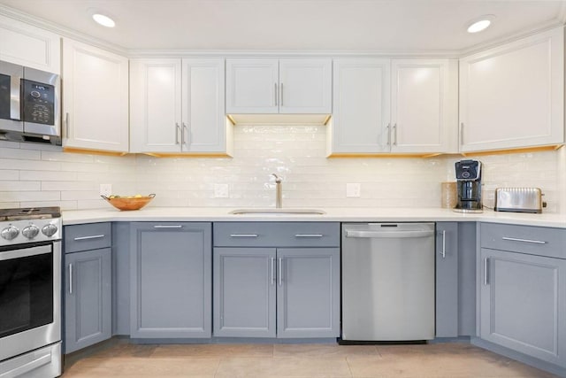 kitchen featuring sink, appliances with stainless steel finishes, white cabinetry, backsplash, and light tile patterned flooring