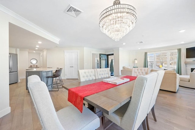 dining space featuring ornamental molding, a notable chandelier, and light hardwood / wood-style flooring