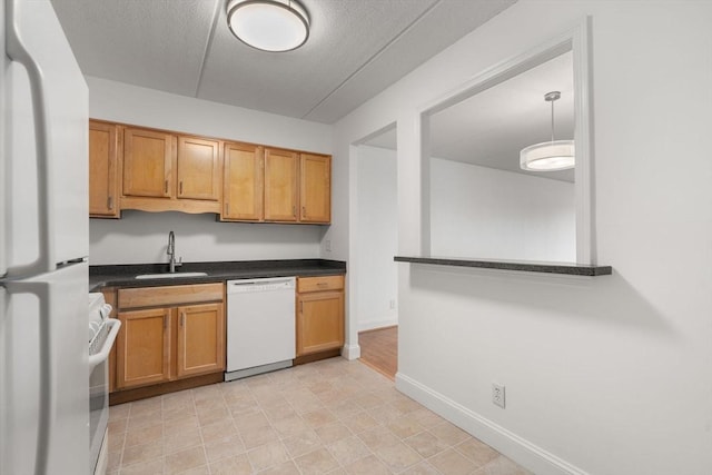 kitchen featuring sink, a textured ceiling, white appliances, and decorative light fixtures