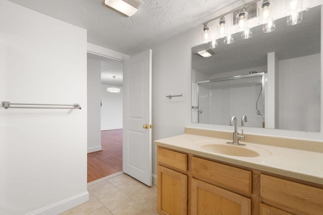 bathroom featuring walk in shower, tile patterned floors, vanity, and a textured ceiling