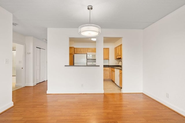 unfurnished living room featuring sink and light hardwood / wood-style floors