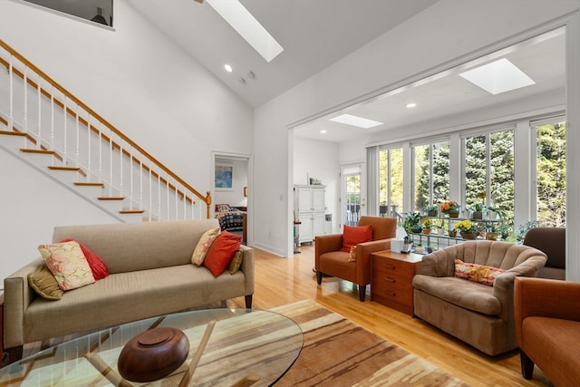 living room with light wood-type flooring, high vaulted ceiling, and a skylight