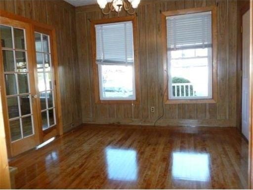 6 Newton Ave, Worcester, MA 01602 - empty room featuring a chandelier, wooden walls, wood finished floors, and healthy amount of natural light