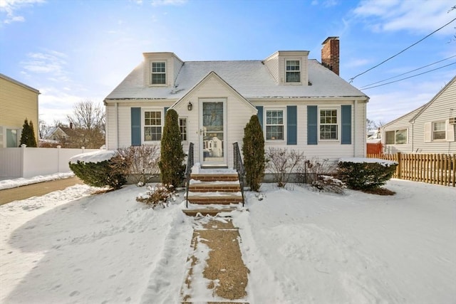 cape cod-style house featuring a chimney and fence