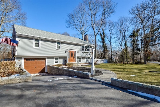 raised ranch featuring a garage and a front yard