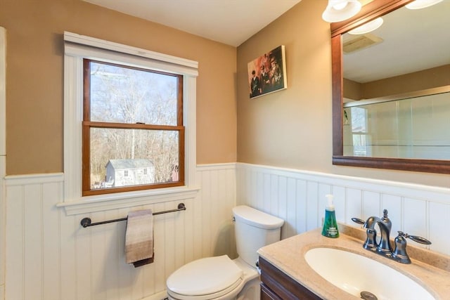 bathroom featuring vanity, a shower with shower door, and toilet