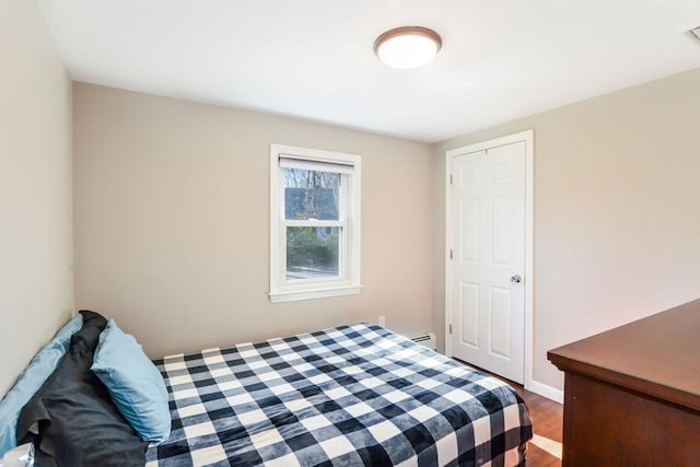 bedroom with dark wood-type flooring and a baseboard radiator