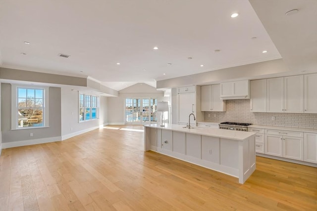 128 Elm St Unit 312, Cohasset, MA 02025 - kitchen with open floor plan, light countertops, tasteful backsplash, light wood-style flooring, and an island with sink