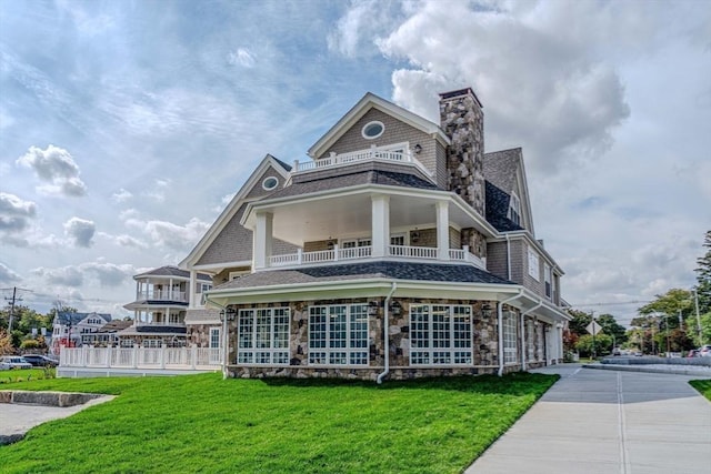128 Elm St Unit 312, Cohasset, MA 02025 - view of front of home with a balcony, stone siding, a chimney, a front lawn, and a shingled roof
