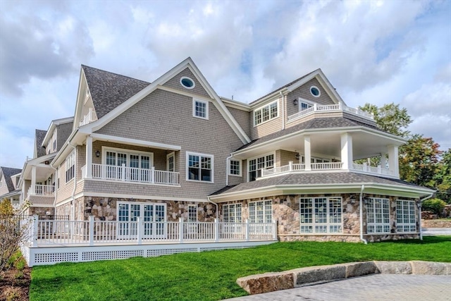 128 Elm St Unit 312, Cohasset, MA 02025 - rear view of house with stone siding, a balcony, a lawn, and roof with shingles