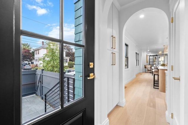 doorway to outside featuring light wood-type flooring, plenty of natural light, and crown molding