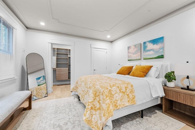 bedroom with wood-type flooring, a walk in closet, ornamental molding, and a closet