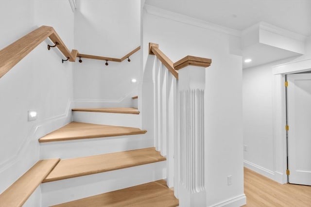 stairs featuring hardwood / wood-style floors and ornamental molding