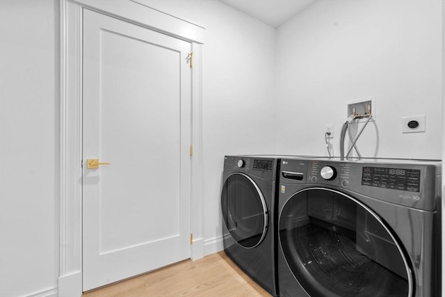 laundry area featuring separate washer and dryer and light hardwood / wood-style floors