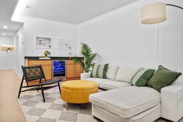 living room featuring wet bar, crown molding, beverage cooler, and light hardwood / wood-style flooring