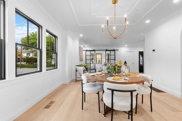 dining space featuring a barn door, an inviting chandelier, light hardwood / wood-style flooring, and crown molding