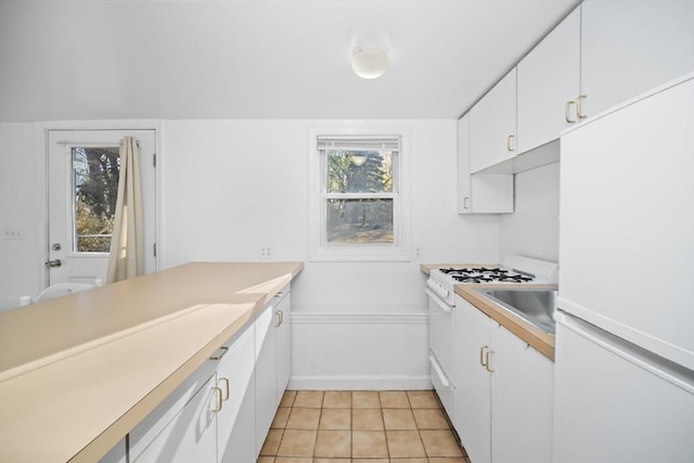 kitchen featuring light tile patterned floors, white cabinets, white appliances, and sink