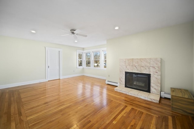 unfurnished living room featuring a fireplace, light hardwood / wood-style floors, baseboard heating, and ceiling fan