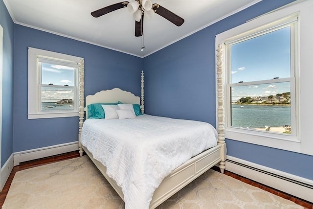 bedroom featuring a baseboard heating unit, baseboards, wood finished floors, ornamental molding, and multiple windows