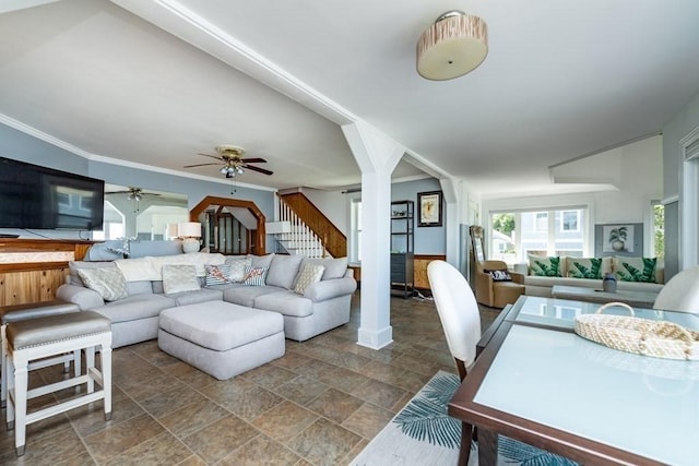 living room featuring plenty of natural light, a ceiling fan, stairs, stone finish flooring, and ornamental molding