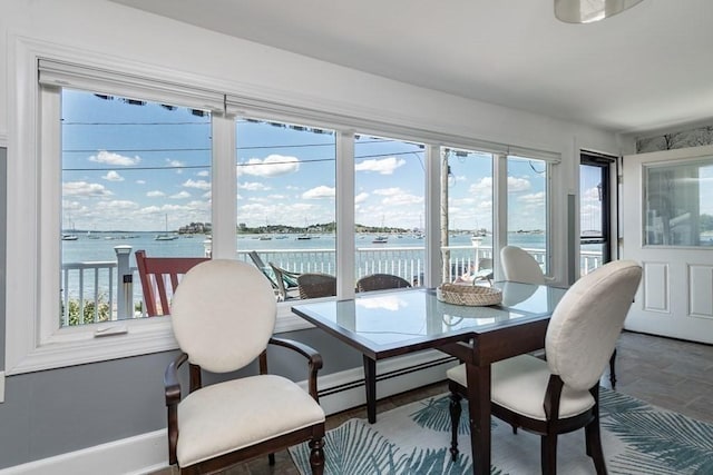 dining area featuring plenty of natural light, a baseboard radiator, a water view, and baseboards