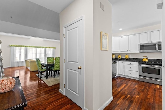 kitchen featuring white cabinets, dark countertops, appliances with stainless steel finishes, and dark wood-style floors