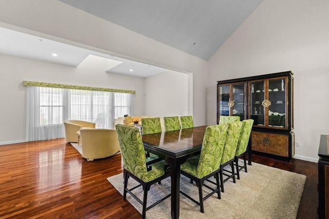dining room with baseboards, high vaulted ceiling, and wood finished floors