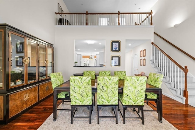 dining area with a high ceiling, wood finished floors, and stairway